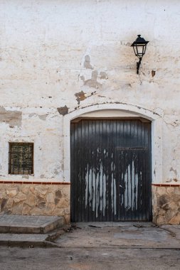 Eski bir kapısı, penceresi ve eski bir feneri olan soyulmuş beyaz bir cephe.