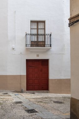 İspanya 'nın Extremadura eyaletinde Plasencia şehrinde bir caddede demir parmaklıklı ahşap bir kapı ve balkonu olan görkemli bir evin cephesi..