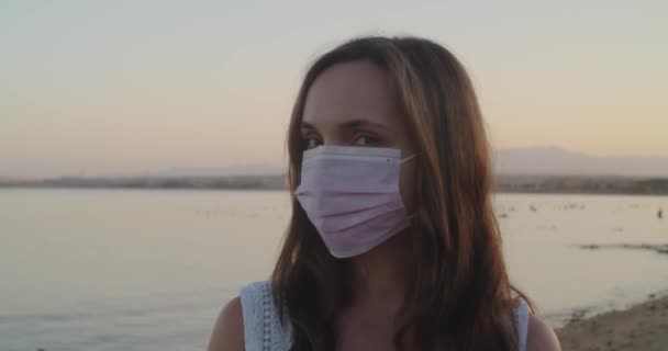 Портрет жінки в медичній масці обличчя на громадському пляжі . — стокове відео