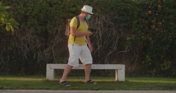 Tourist man in a medical mask looks for his way in a smartphone — Stock Video