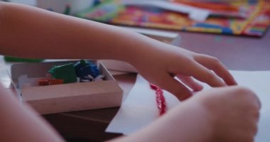 Küçük bir çocuk masada oturan parlak kil ya da plastikle oynar..