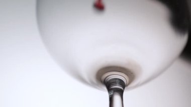 Kırmızı şarap bir şarap bardağına dökülüyor. Beyaz arka plan..