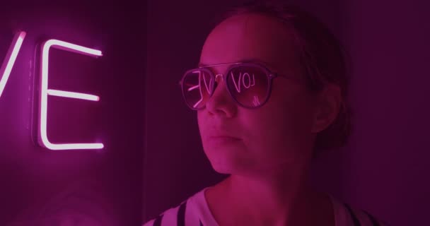 Белые светящиеся буквы Любовь отражается в очках молодой женщины — стоковое видео