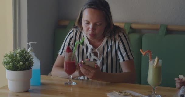 Дама з симетричними типами волосся на смартфоні за столом кафе — стокове відео