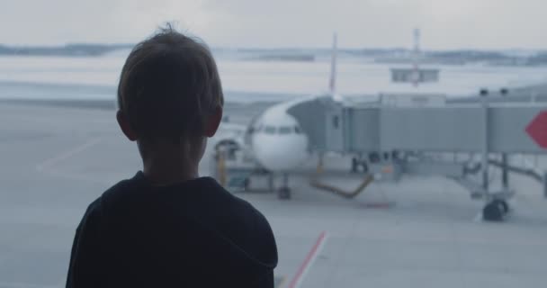 Neugieriger Junge blickt aus Panoramafenster auf großes Flugzeug — Stockvideo