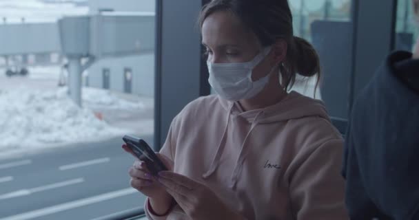 Mulher em máscara protetora usa telefone à espera de voo — Vídeo de Stock
