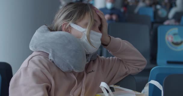 Trött kvinna i mask med resekudde väntar på flyg — Stockvideo