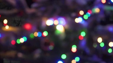 Çok renkli LED dizgi ışıklarının karanlık bir gece arkaplanına karşı yumuşak bokeh küreler yarattığı soyut, bulanık bir görünüm. Kırmızı, yeşil, mavi ve sarı ışıklar yanıp sönüyor. Bayram havasını çağrıştırıyor..