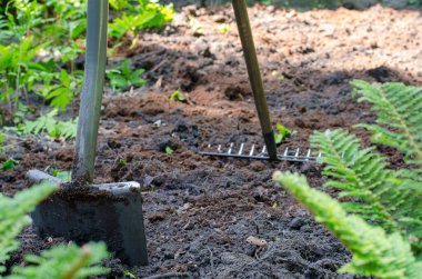 Bahçe aracı (tırmık ve kürek) yerde duruyor, sıkışmış iz