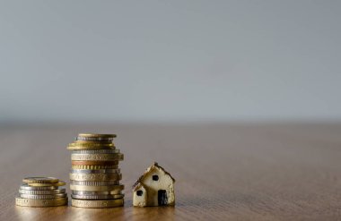 Küçük plastik ev modeli ve bozuk paralarla ev kredisi kavramı