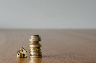 Küçük plastik ev modeli ve bozuk paralarla ev kredisi kavramı