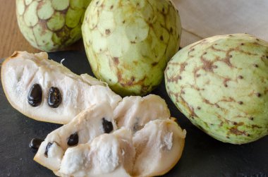 Meyveli Cherimoya ve siyah taş bir masada birkaç dilim. Kapat..