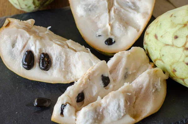 Siyah taş bir masada dilimlenmiş Cherimoya. Kapatın. Üst görünümü aç