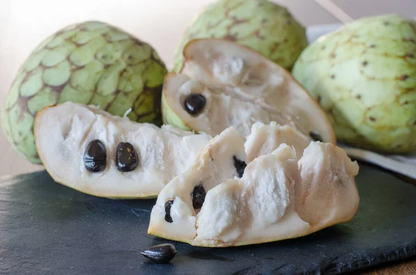 Siyah taş bir masada dilimlenmiş Cherimoya. Kapat..