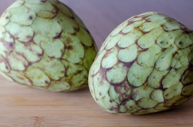 Ahşap masa arkasında Cherimoya meyvesi. İki Cherimoyas. Kapat.