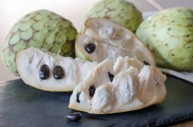Siyah taş bir masada dilimlenmiş Cherimoya. Kapat..