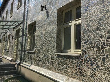 Ayna mozaiğiyle kaplı bir evin dış cephesinin fotoğrafı. Aynalarla yüz yüze. Polonya, Lodz, Piotrkowska Caddesi.