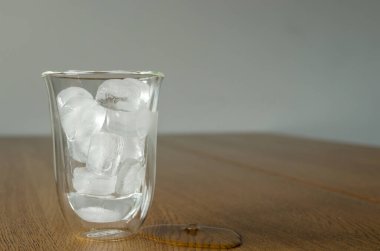 Eriyen buz parçaları ve ahşap masanın üzerinde bir parça buz.