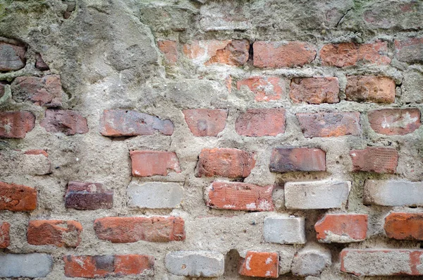 old grey concrete garage wall with red bricks and cracks abstract background