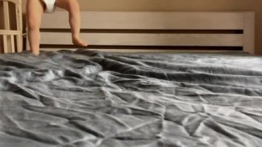 İki çocuk kardeş (erkek) büyük ebeveynlerin yatağında zıplıyorlar. Çerçevede sadece bacaklar var. Ev karantinasında tecrit. Mutlu çocukluk kavramı.  