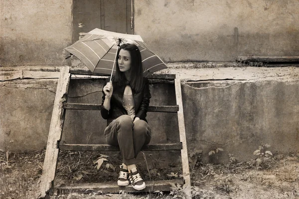 Obra em estilo retro, jovem com guarda-chuva sentado perto de t — Fotografia de Stock