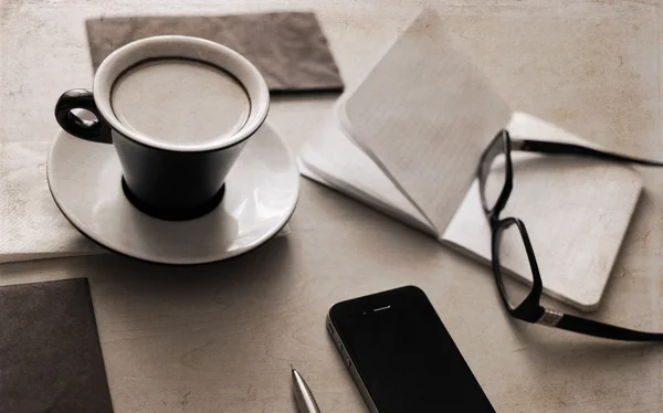 Konstverk i retrostil, kopp kaffe, glasögon, notebook — Stockfoto