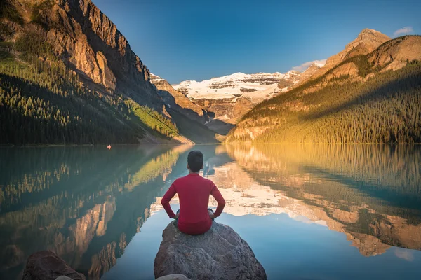 Άνθρωπος κάθεται σε βράχο βλέποντας Λίμνη Λουίζ αντανακλάσεις — Φωτογραφία Αρχείου