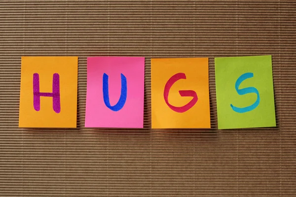Abraços texto em notas pegajosas coloridas — Fotografia de Stock