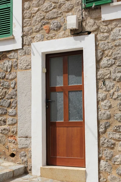 Brown wooden door in stone wall, mediterranean style — Stock Photo, Image