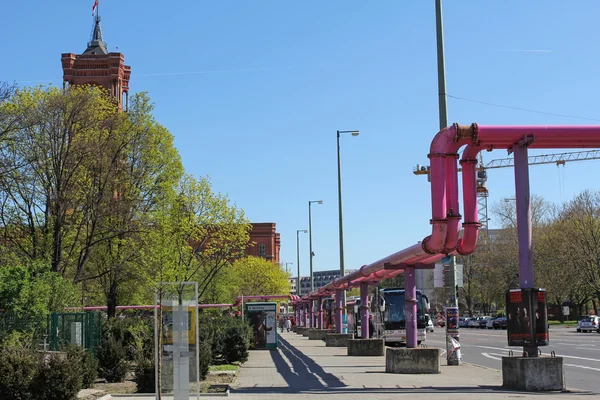 Berlin, 21. april 2016: das rotes rathaus hinter den bäumen und rosa rohren am alexanderplatz in berlin — Stockfoto