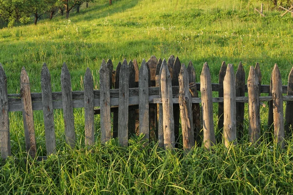 Cerca de madeira rural no prado verde — Fotografia de Stock