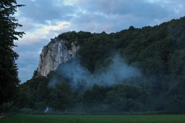 Humo de un fuego debajo de una montaña de piedra caliza por la noche —  Fotos de Stock