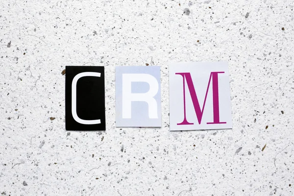 CRM (Customer Relationship Management) acrónimo cortado de periódico en textura de papel blanco hecho a mano — Foto de Stock