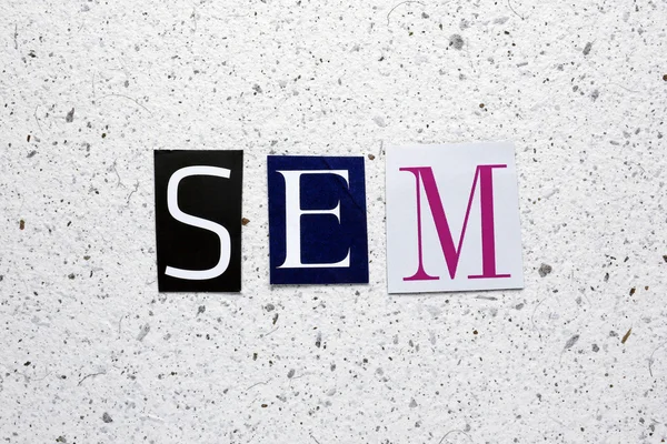 SEM (Search Engine Marketing) akronym klippt från tidningen i vita handgjorda pappersstruktur — Stockfoto