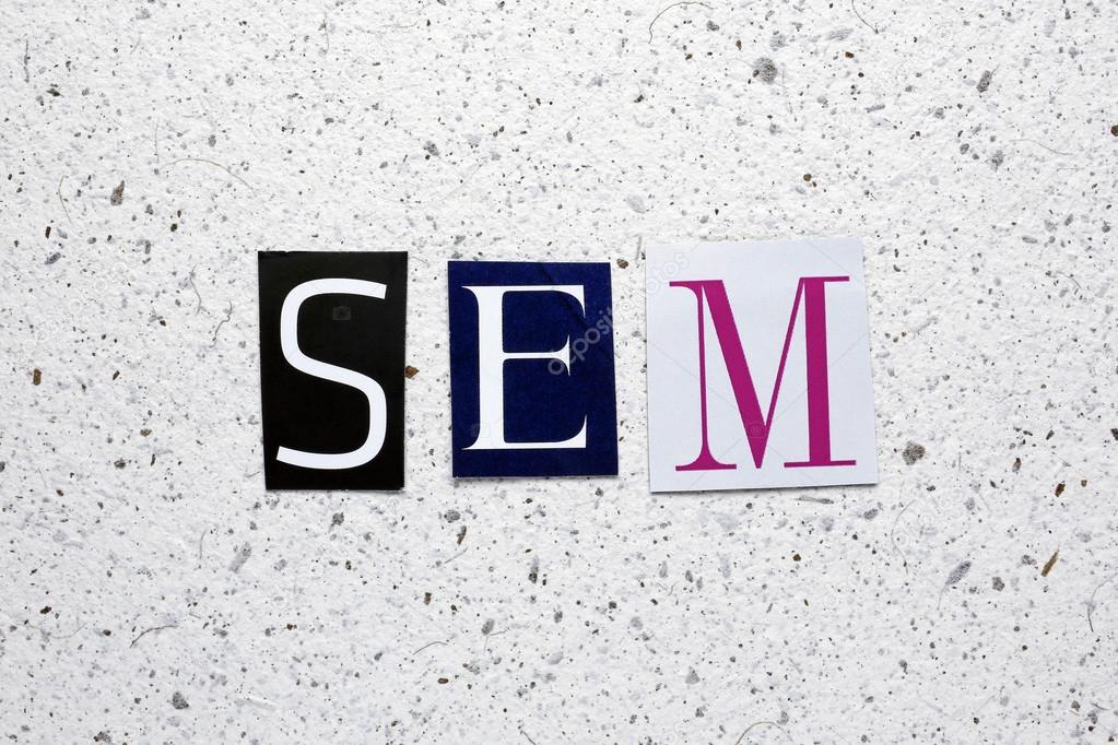 SEM (Search Engine Marketing) acronym cut from newspaper on white handmade paper texture