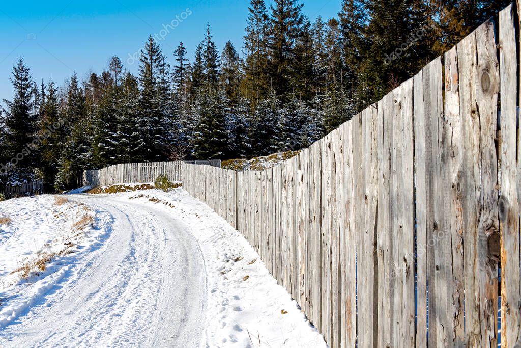 winter snowy road with wooden fence