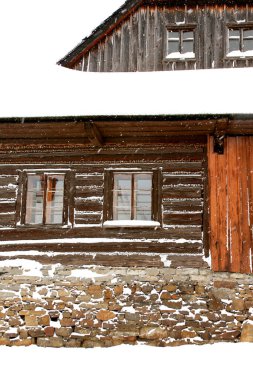 Kar fırtınası sırasında bir taş temeli üzerinde ahşap bir ev cephesi