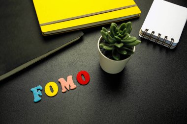 FOMO (kaçırılma korkusu) Siyah masanın üzerindeki renkli keçeli harflerle yazılan kısaltma