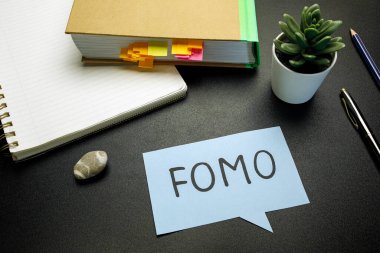 FOMO (kaçırılma korkusu) siyah masadaki kağıt konuşma baloncuğuna yazıldı