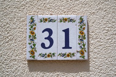 Beyaz duvardaki dekore edilmiş seramik fayanslar 31 ev numarası