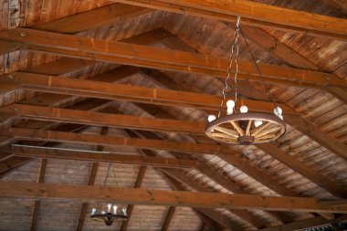 Ahşap tavandan sarkan ahşap araba tekerleğinden yapılmış kırsal avize.