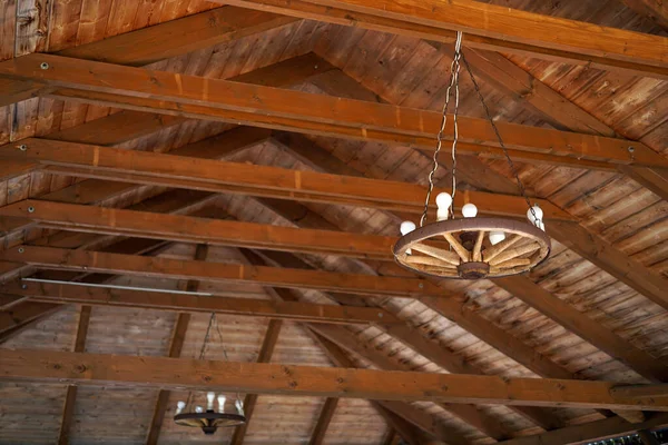 Ahşap tavandan sarkan ahşap araba tekerleğinden yapılmış kırsal avize.