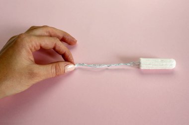 Kadın eli, pembe kağıt dokusundaki temiz pamuk tamponunun ipini çeker.