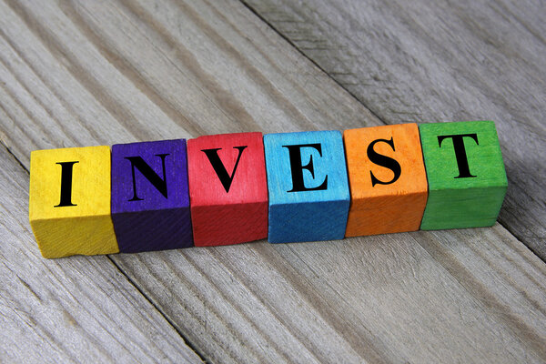 Word invest on wooden colorful cubes