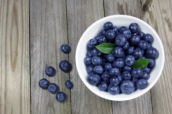 Blueberries in porcelain bowl on wooden background — Stock Photo, Image