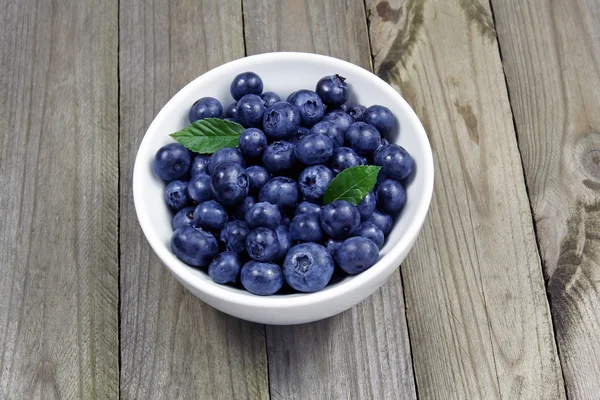 Blueberries in porcelain bowl on wooden table — Stock Photo, Image