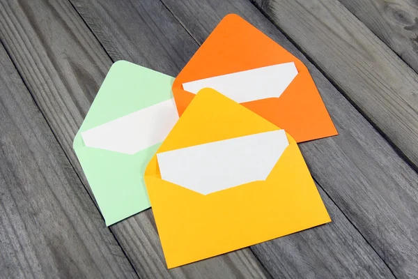 Three colorful open envelopes with blank cards on wooden background — Stock Photo, Image