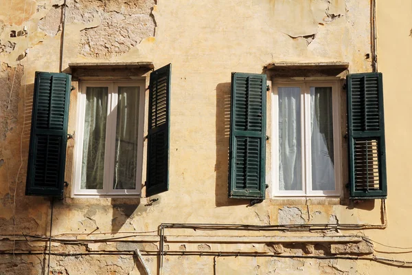 Grungy vägg med fönster med fönsterluckor i trä — Stockfoto