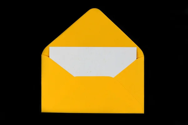 Yellow open envelope with blank card on black background — Stock Photo, Image