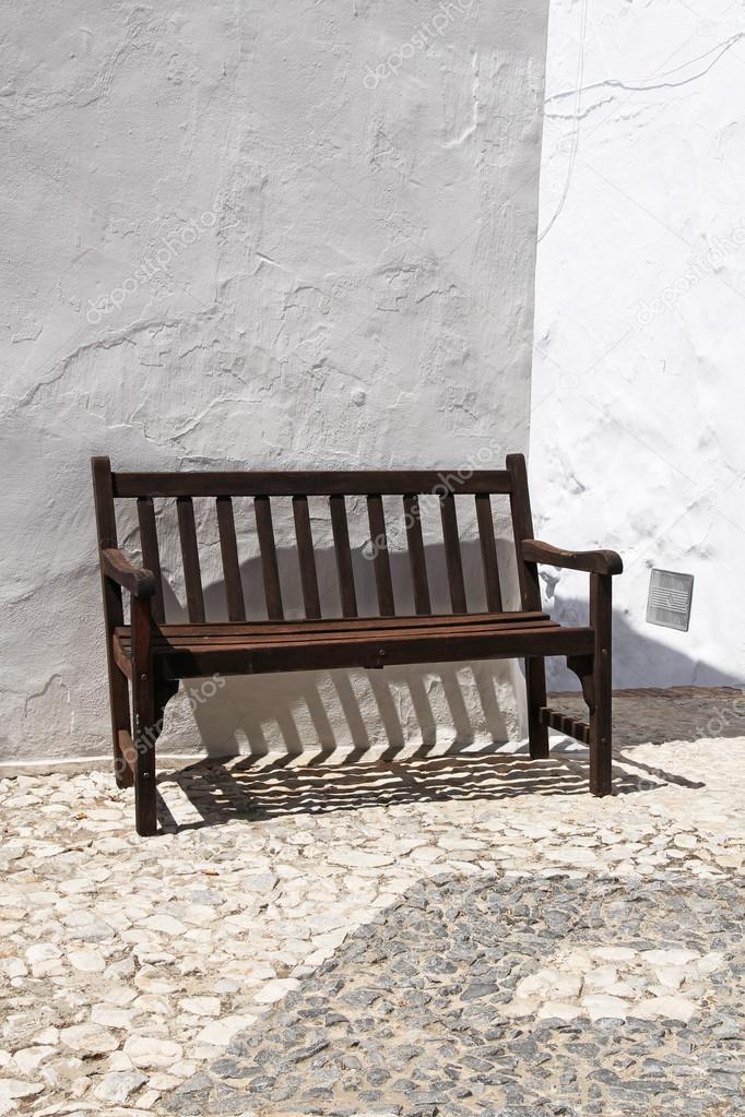 Vintage wooden bench against whitewashed wall